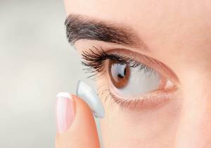 Closeup of woman putting contact lense into her eye